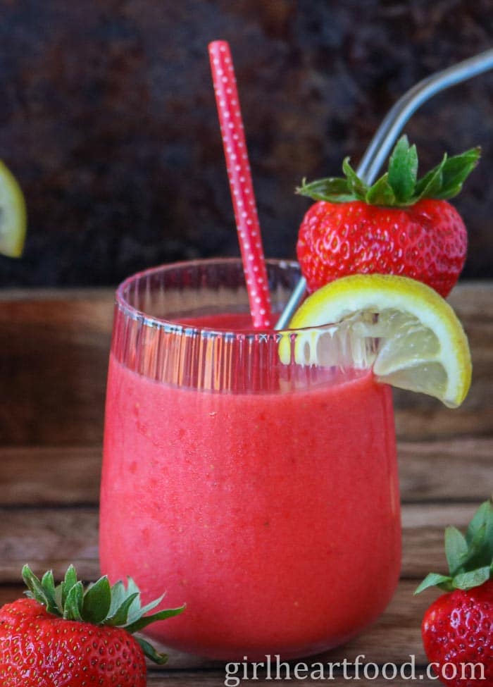 Glass of a frozen strawberry lemonade next to strawberries.