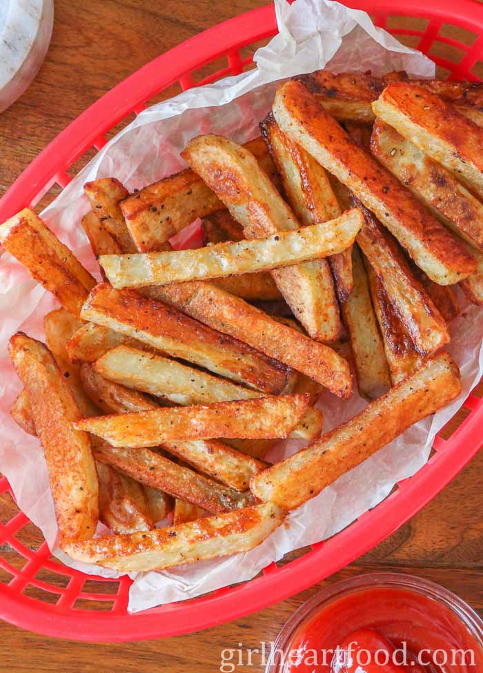 Close-up of a basket of baked fries next to a dish of ketchup.