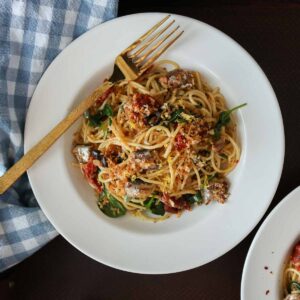 Bowl of sardine pasta with a gold fork resting on the bowl.
