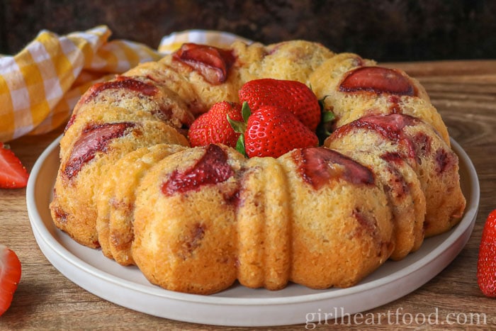 Strawberry cake with fresh strawberries in the centre, sitting on a plate.