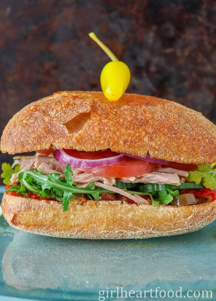 Tuna vegetable sandwich on ciabatta bun with a hot pepper on top.