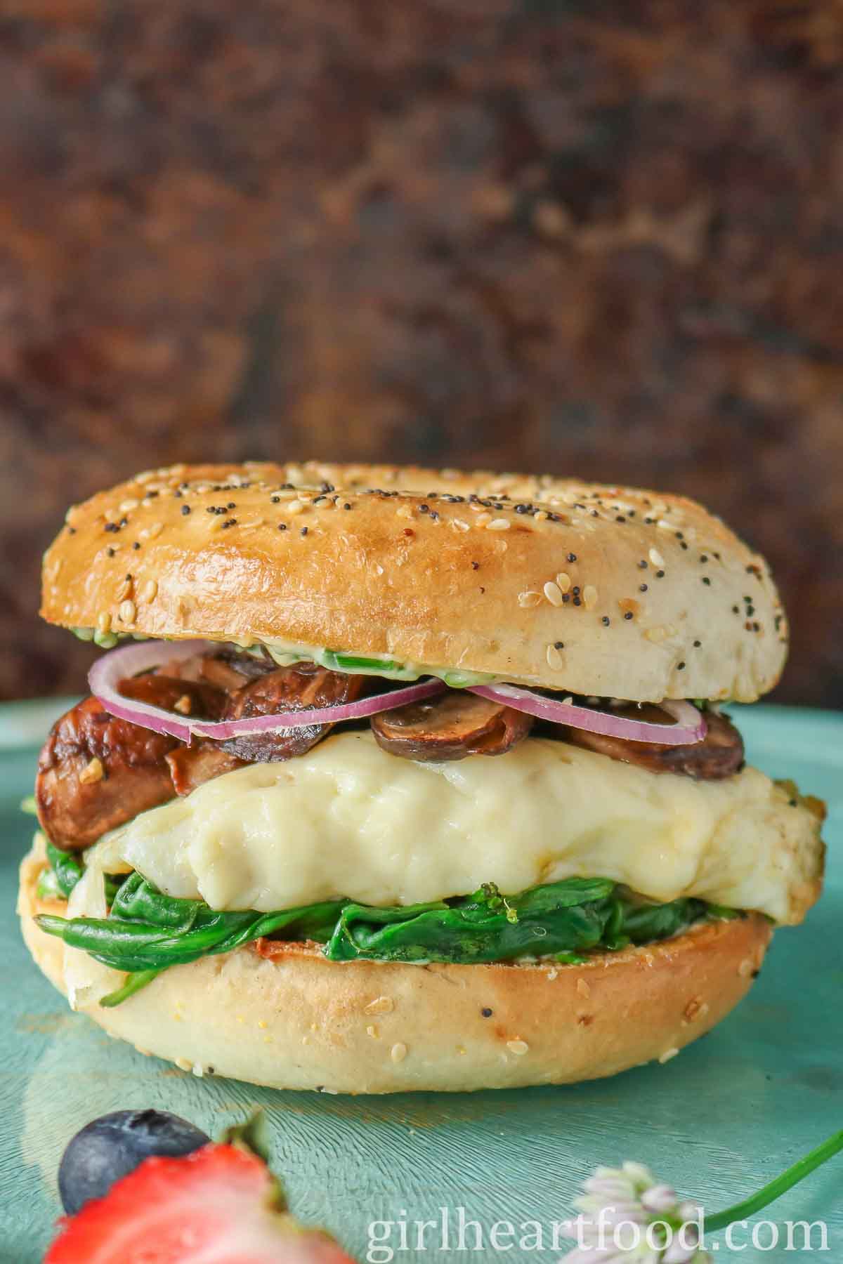 Mushroom, spinach, cheese, egg and onion bagel breakfast sandwich.