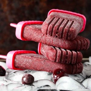 Stack of four cherry vanilla ice pops on a tray of ice cubes.
