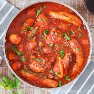 Pan of chicken, sausage, peppers and potatoes in tomato sauce.