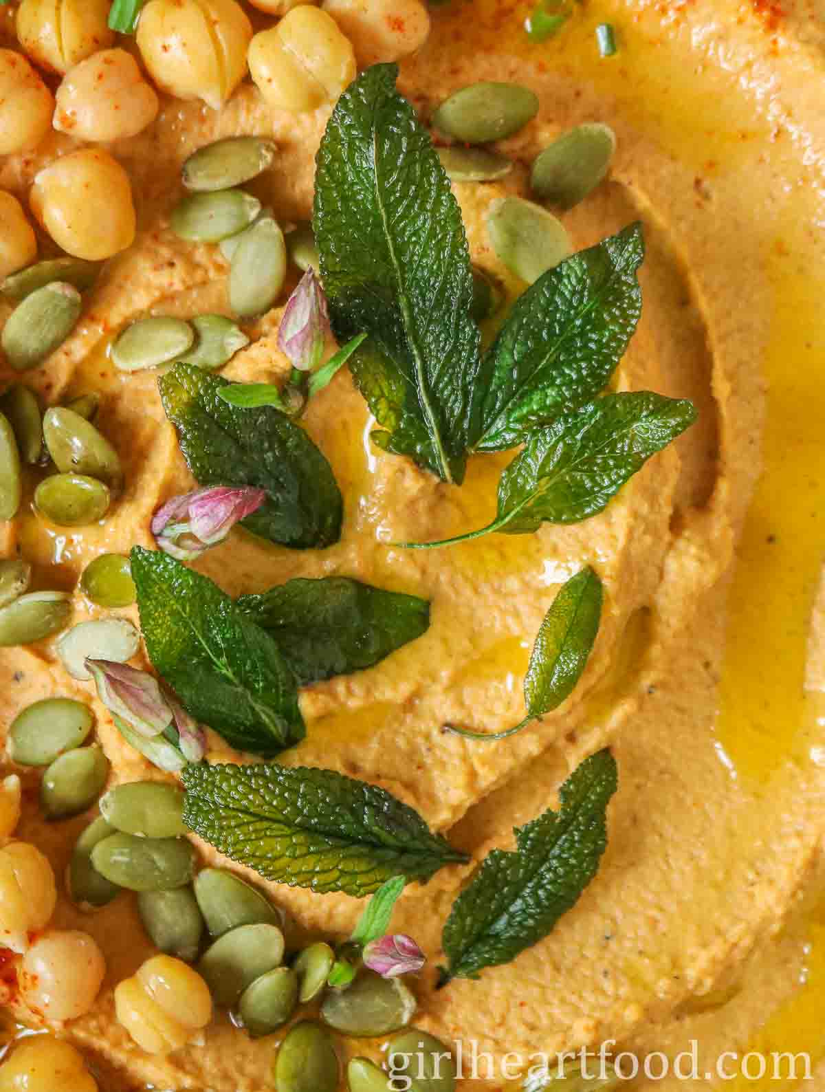 Close-up of crispy sages leaves on top of flavoured hummus.
