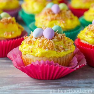 Frosted vanilla cupcakes garnished with candy and coconut.