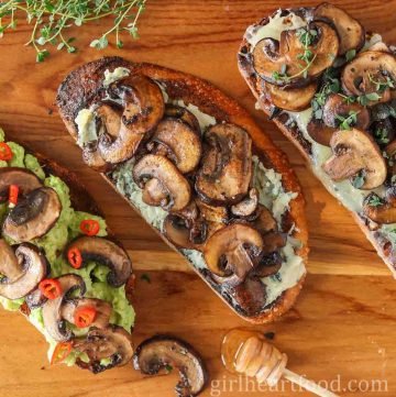 Three slices of mushrooms on toast next to a honey stick.