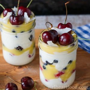 Two layered dessert jars with cherries and coconut on top.