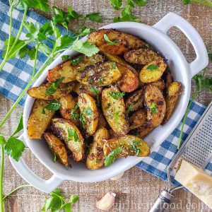 Pesto potatoes in a dish garnished with parsley and Parmesan.