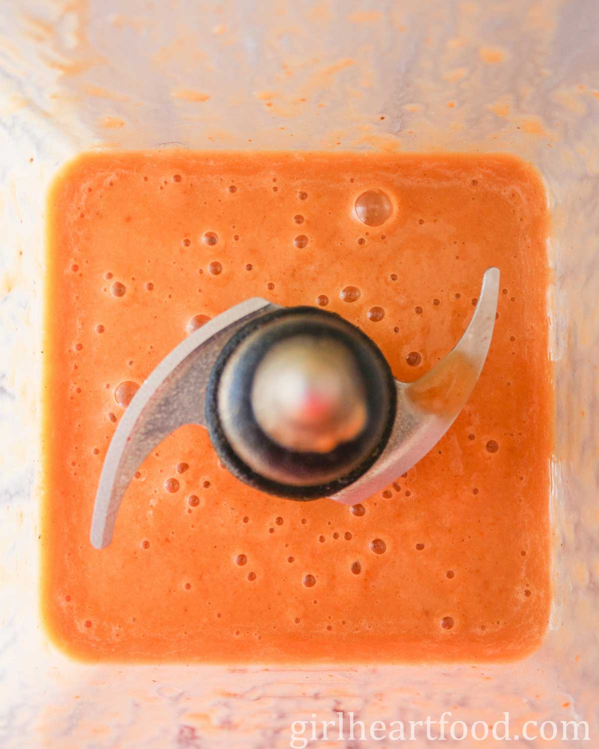 Bright orange coloured smoothie in a blender.