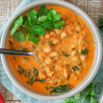 Bowl of red lentil chickpea soup garnished with cilantro.