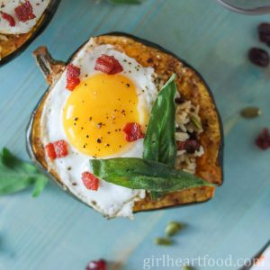 Roasted stuffed acorn squash topped with a fried egg, crispy bacon and sage leaves.