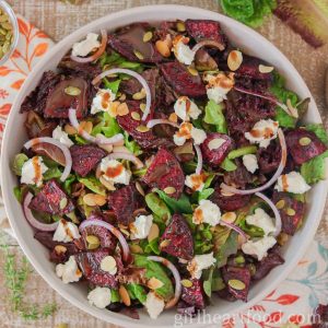 Roasted beet salad in a bowl with balsamic vinaigrette drizzled over top.