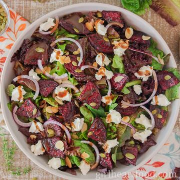 Roasted beet salad in a bowl with balsamic vinaigrette drizzled over top.