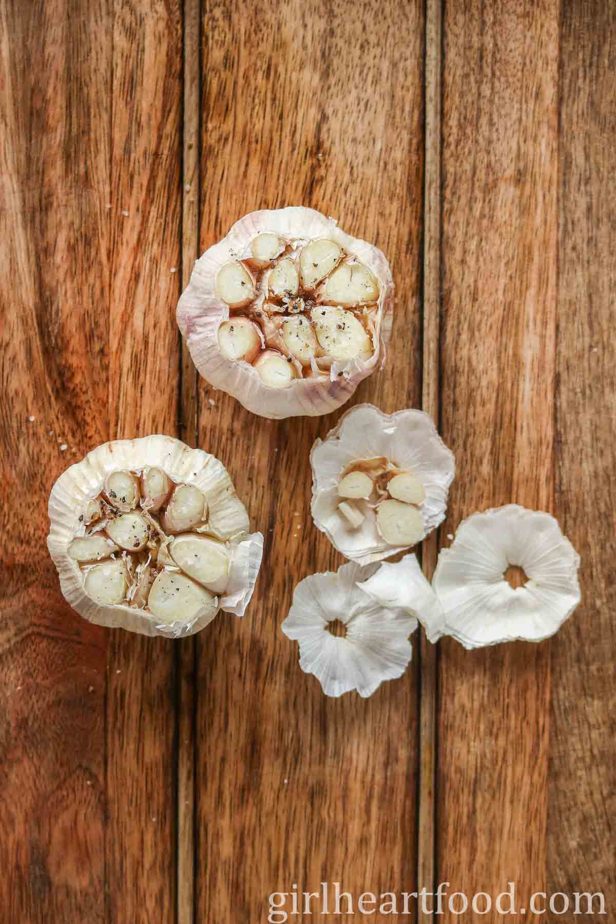 Two bulbs of garlic with the tops cut off, exposing the cloves inside.