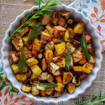 Roasted root vegetables in a dish garnished with herbs.