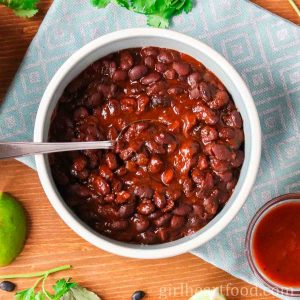 Bowl of baked black beans with a spoon dunked into them.