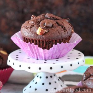 Triple chocolate muffin with purple liner on a polka dot stand.