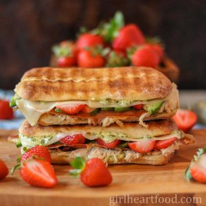 Stack of two turkey panini sandwiches next to strawberries.