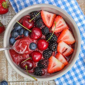 Fruit smoothie bowl garnished with lots of fresh berries and cherries.