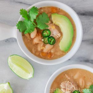 Two bowls of white chicken chili with toppings.