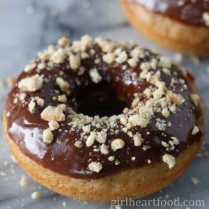 Close-up of a glazed baked donut with crushed peanuts.