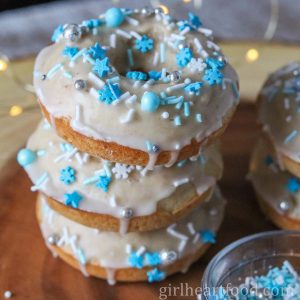 Stack of three glazed eggnog donuts with sprinkles.