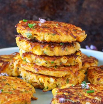 Stack of five butternut squash fritters surrounded by more fritters.