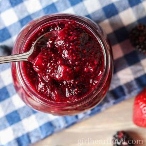 Jar of berry chia seed jam with a spoon resting in it.