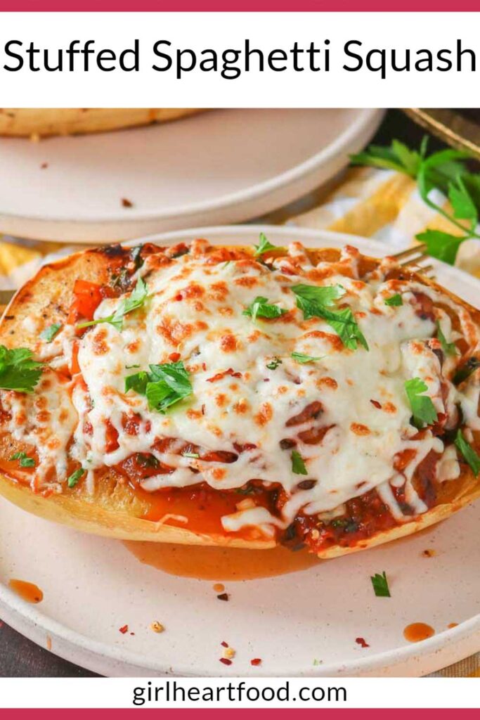 Cheesy stuffed spaghetti squash boat on a plate in front of another plate of stuffed squash.