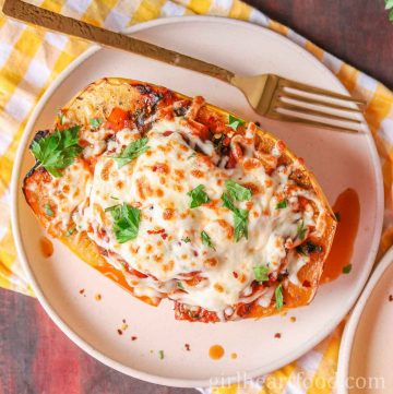 Cheesy stuffed spaghetti squash boat and fork on a plate.