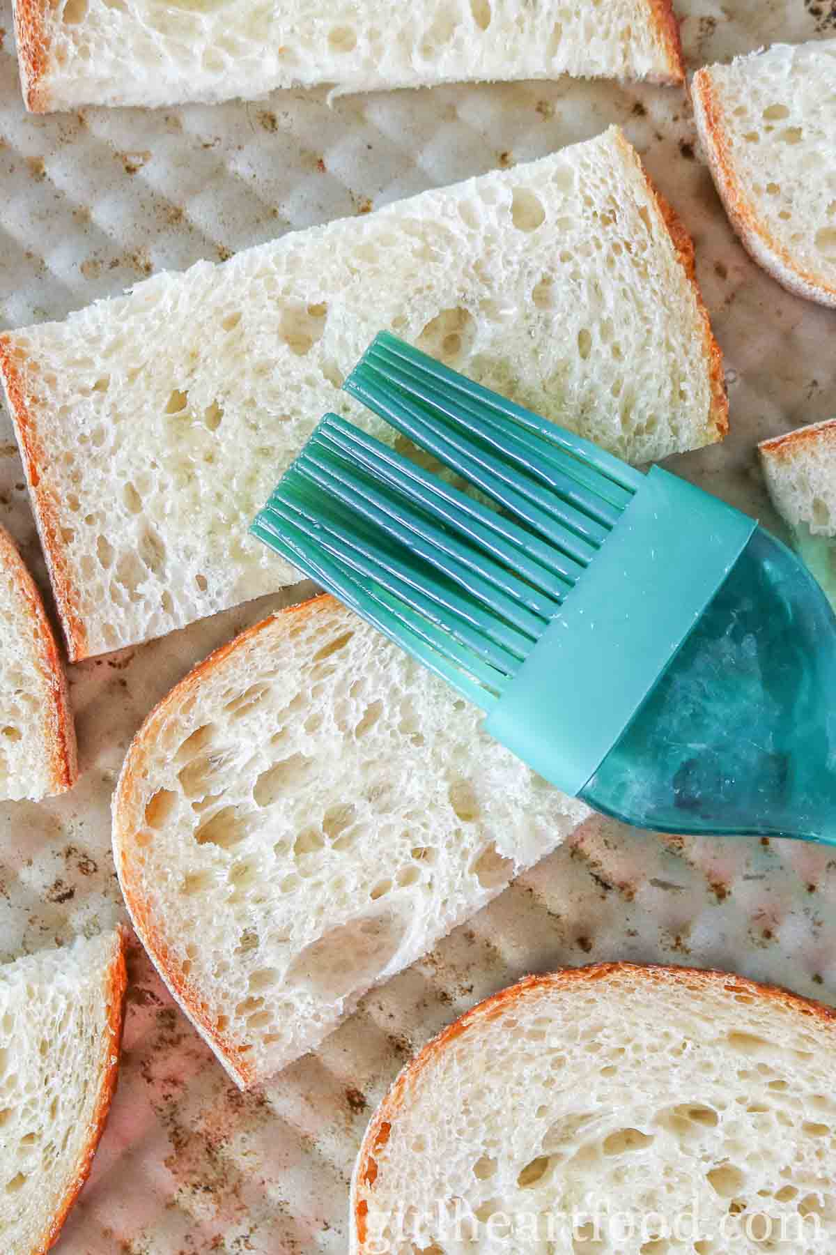 Brushing olive oil over some bread with a silicone brush.