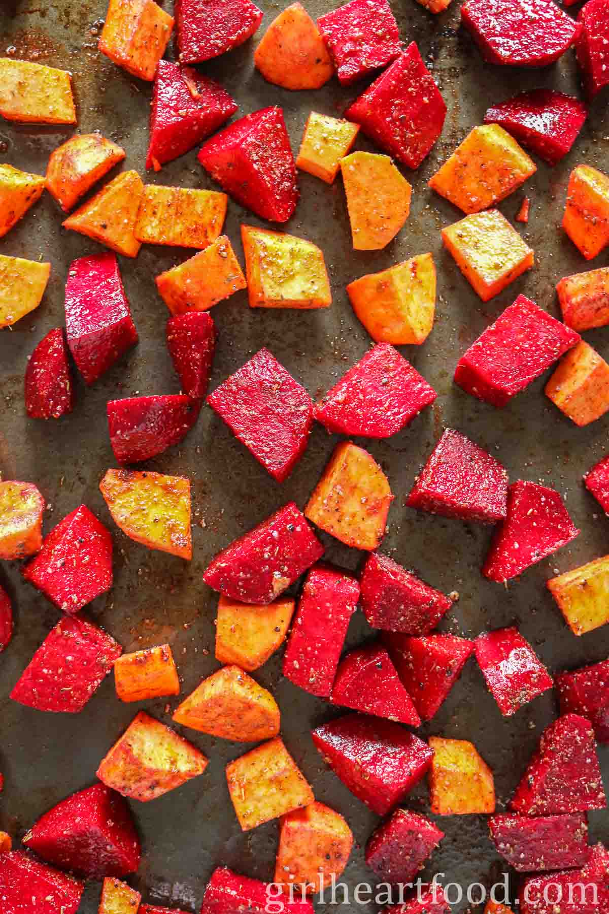 Chunks of beet and sweet potato on a sheet pan before being roasted.