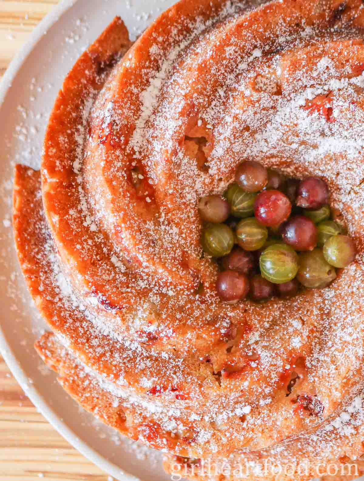 Close-up of an icing sugar dusted gooseberry cake with gooseberries in the centre.