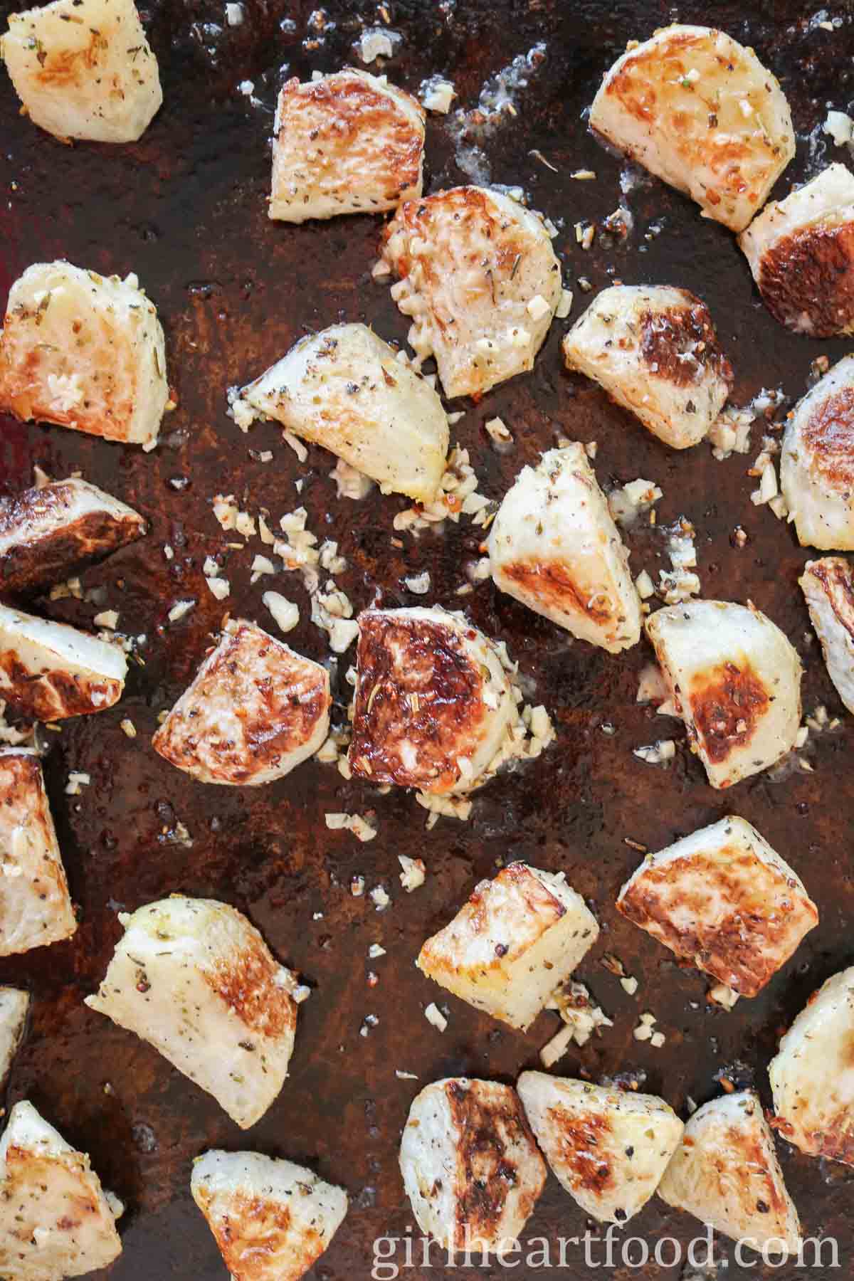 Chunks of roasted kohlrabi on a sheet pan.
