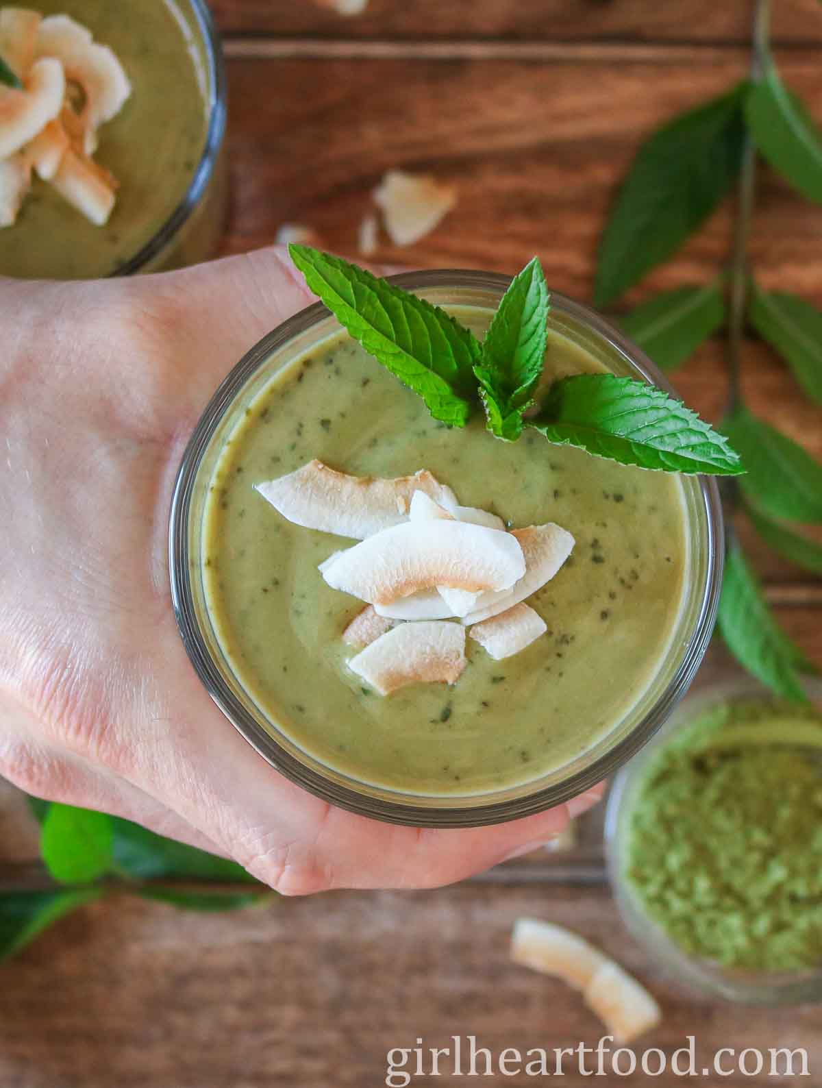 Hand holding a glass of matcha smoothie.