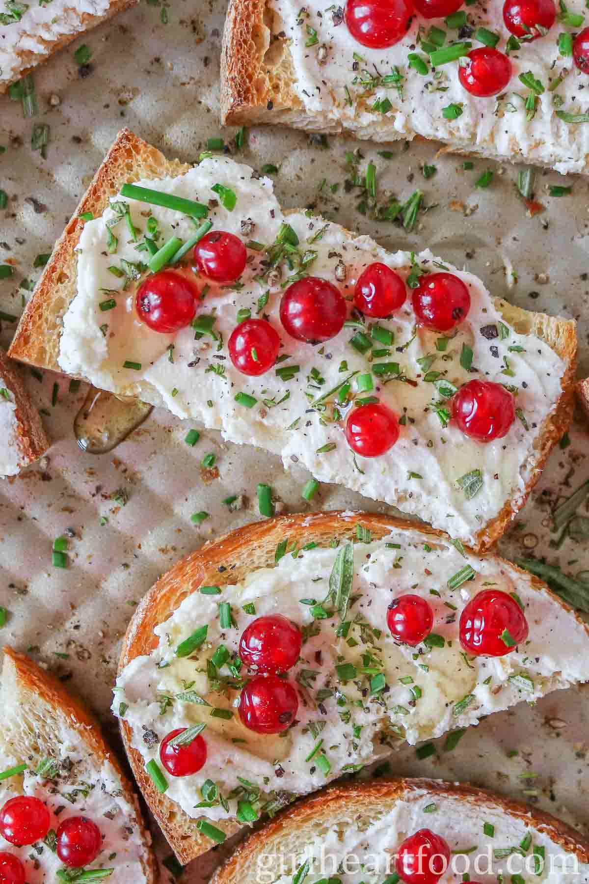 Goat cheese and red currant crostini on a sheet pan.