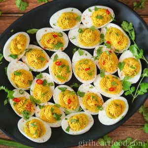 Curry deviled eggs on a black platter.