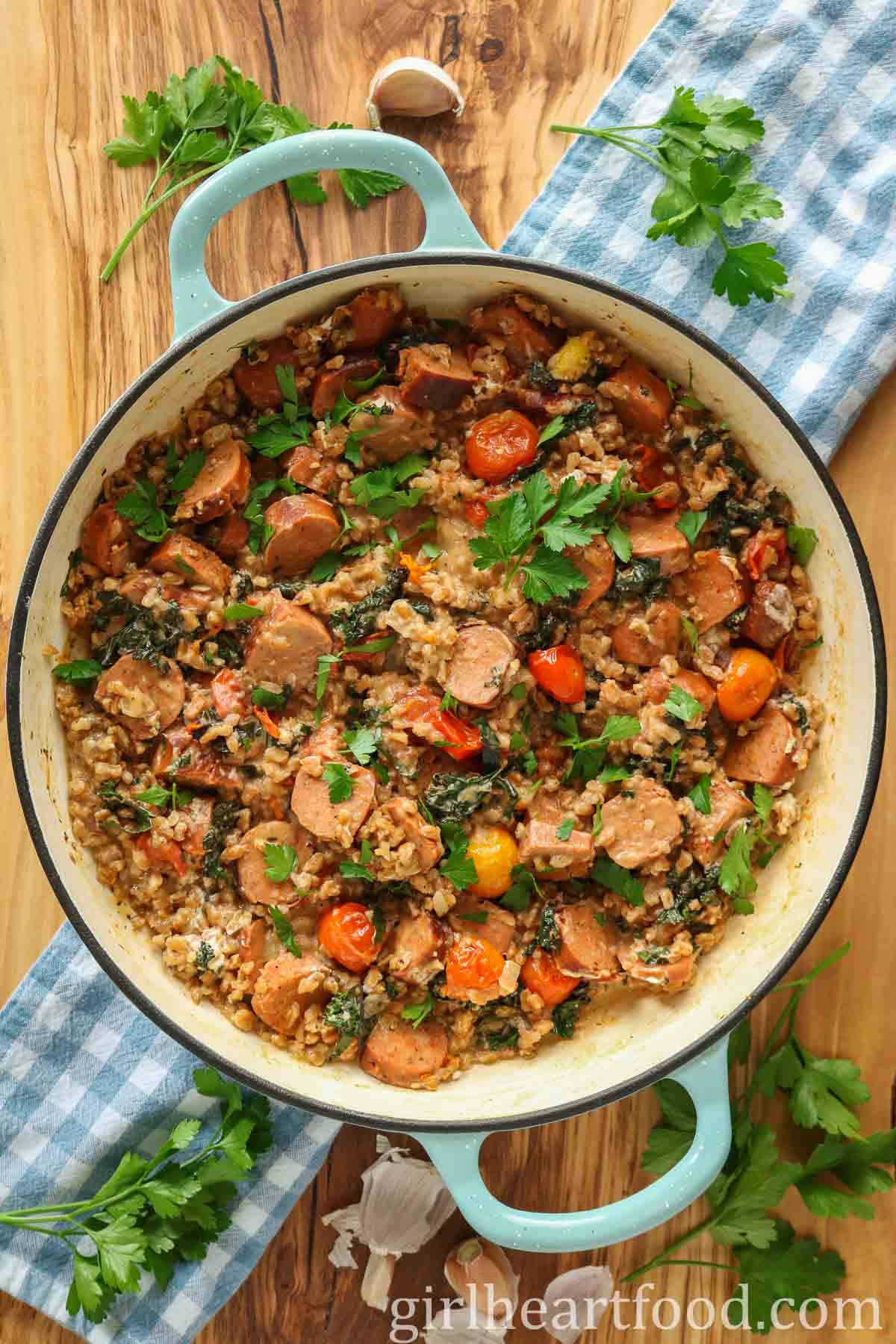 Sausage, farro and vegetables in a pan garnished with fresh parsley.
