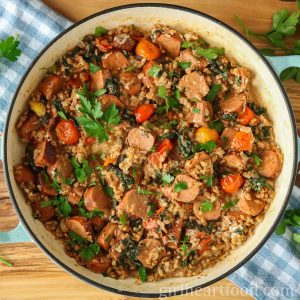 Pan of sausage, farro and vegetables garnished with fresh parsley.