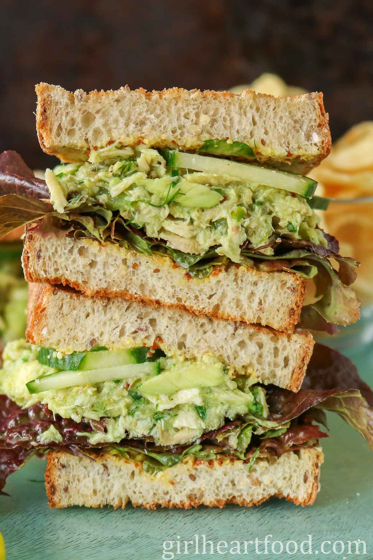 Stack of two halves of a tuna avocado salad sandwich.