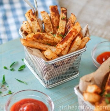 Turnip fries in a steel basket next to a dish of ketchup.