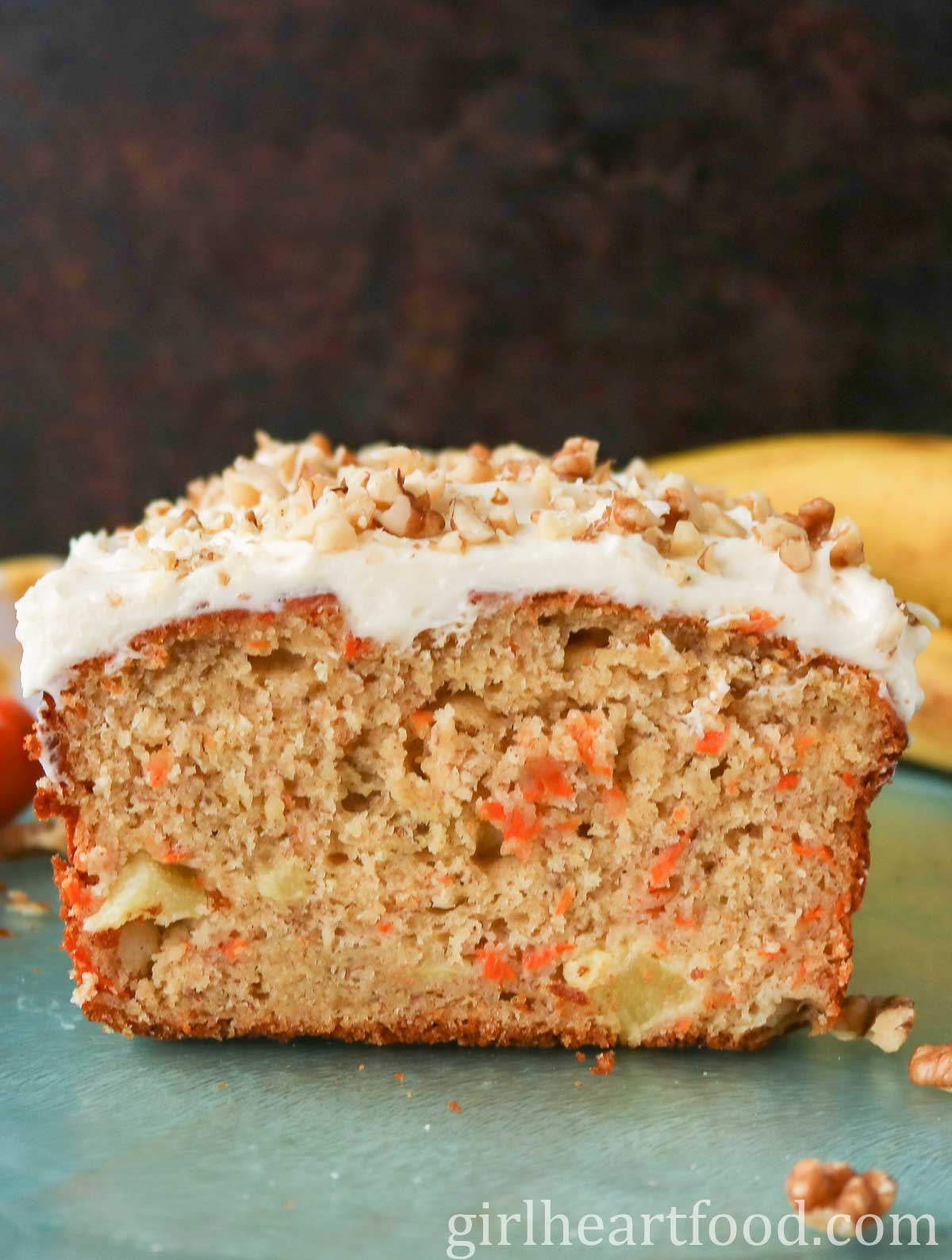 Cut loaf of frosted carrot cake banana bread, showing the interior texture.
