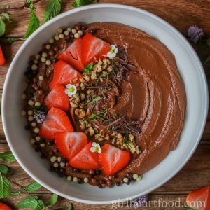 Bowl of chocolate hummus garnished with toppings.