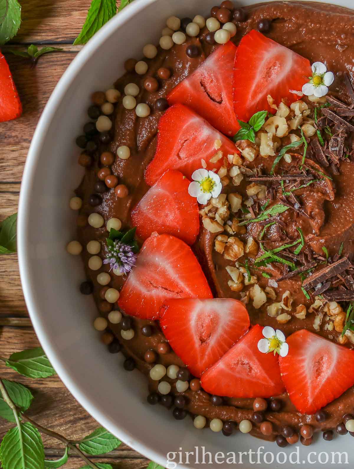 Close-up of a bowl of chocolate hummus garnished with toppings.