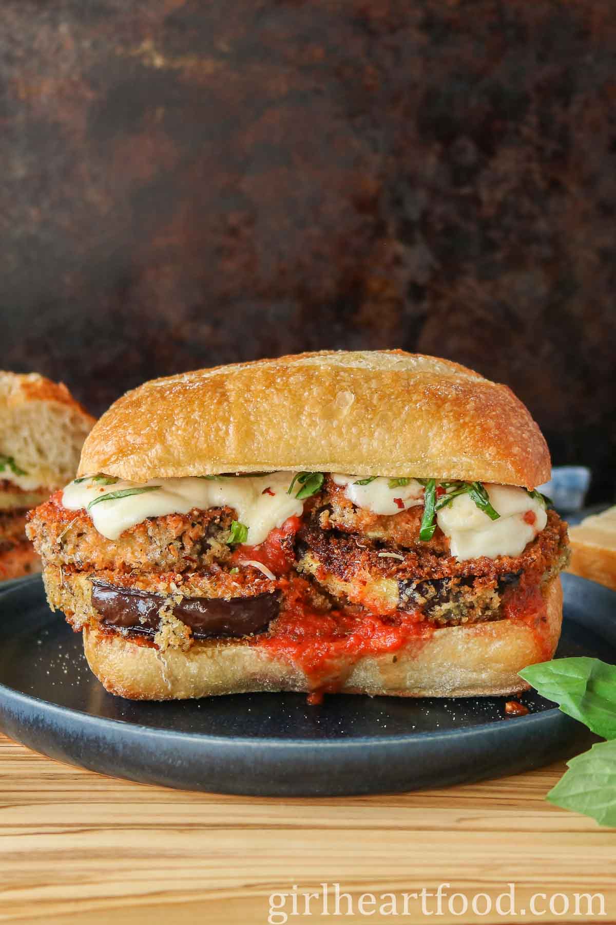 Eggplant Parmesan sandwich on a dark blue plate.