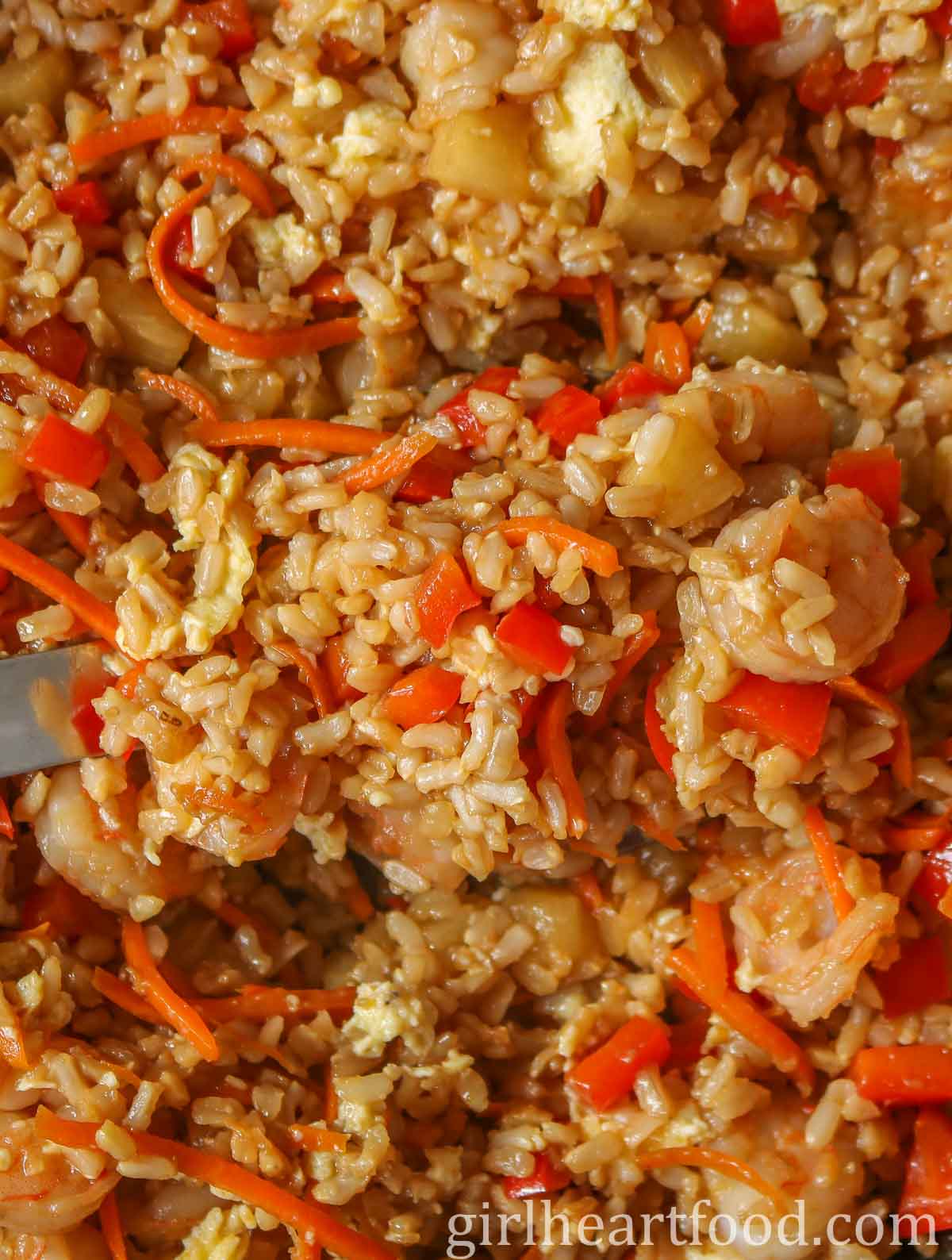 Close-up of fried rice with a serving spoon dunked into it.