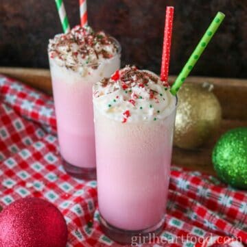 Two glasses of pink candy cane milkshake, one in front of the other.