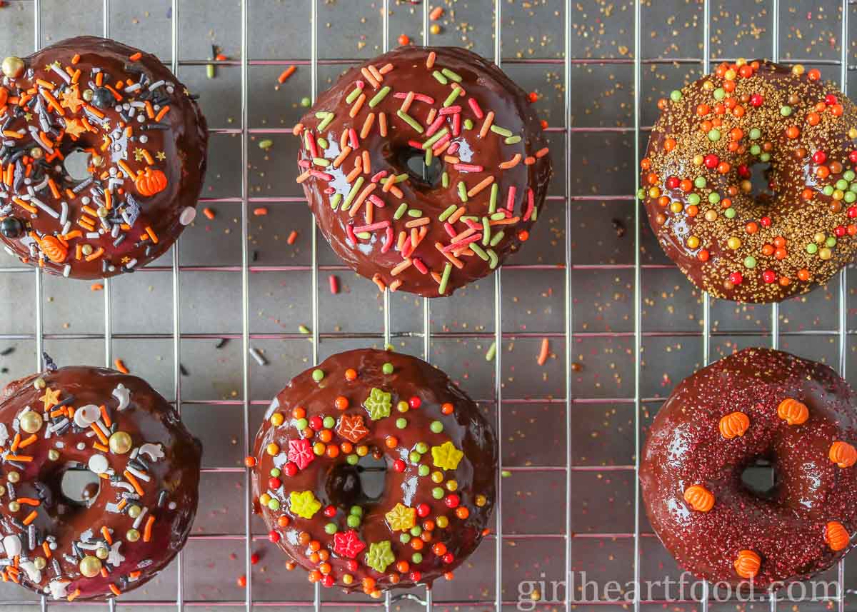 Chocolate glazed donuts with sprinkles on a cooling rack.