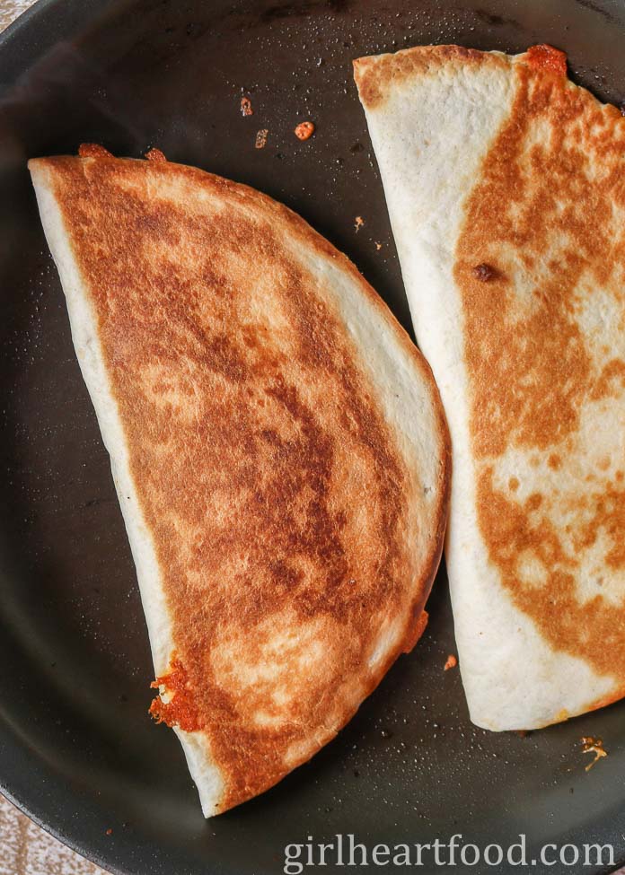 Two quesadillas in a frying pan.